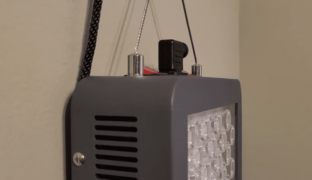 Hooga HG1000 red light therapy panel close up showing metal housing, cooling vents and LED array with hanging kit installed.