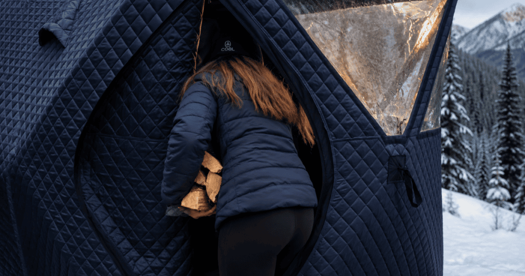 Woman carrying firewood into a Sweat Tent outdoor sauna in winter