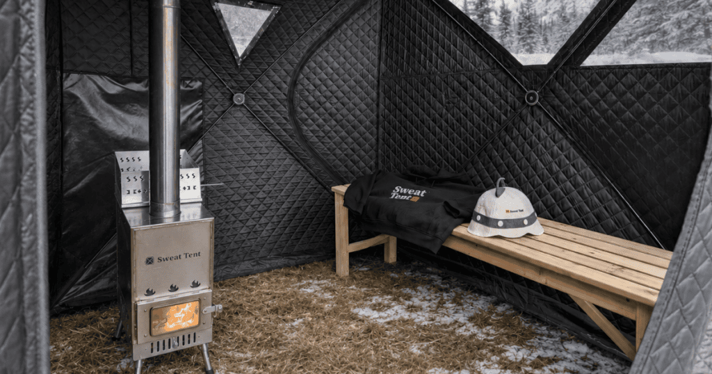 Sweat Tent sauna interior with insulated walls, wood-burning stove, and wooden bench